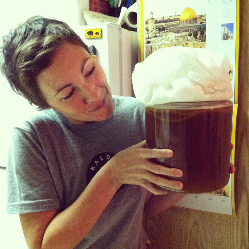 Sarah holds Kombucha Tea with floating SCOBY and foam